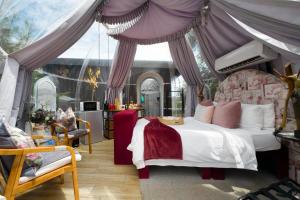 a bedroom with a canopy bed and a chair at The Vino Dome By Once Upon a Dome Franschhoek in Franschhoek
