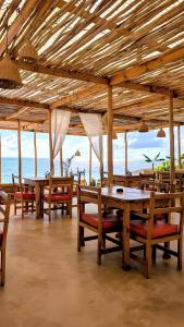 a restaurant with wooden tables and chairs and the ocean at HA Beach Breeze in Jambiani