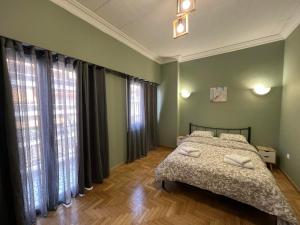 a bedroom with a bed and large windows at Sfiggos 54 Guest House in Athens