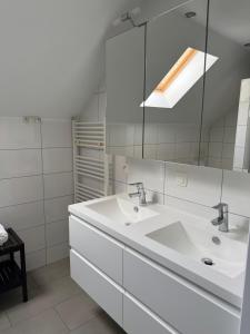 a white bathroom with two sinks and a mirror at B&B Bodegem in Dilbeek