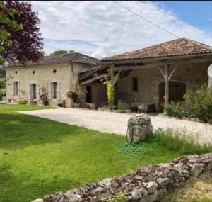 a stone house with a grass yard in front of it at La Maison d'ART in Lacour
