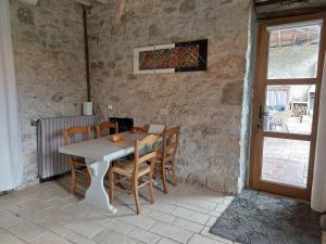 a table and chairs in a room with a stone wall at La Maison d'ART in Lacour