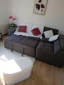 a black couch in a living room with a table at Maison bretonne 119 m2 - jardin clos - 30 min Côte Émeraude in Plénée-Jugon