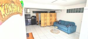 a living room with a blue couch and a kitchen at Studio XL 4 places in Ducos