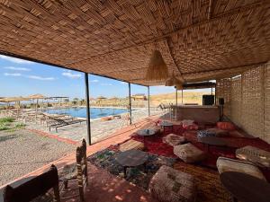 a living room with tables and chairs and a pool at Be Nomad Agafay Camp in El Karia