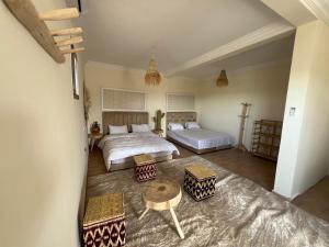 a large bedroom with two beds and a table at Be Nomad Agafay Camp in El Karia +44 photos