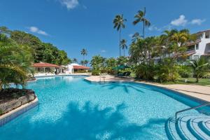 a large swimming pool with palm trees in a resort at Glitter Bay Apartment 104 in Saint James