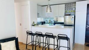 a kitchen with a bar with four stools at Viabo in Viña del Mar