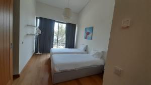a white room with two beds and a window at Tróia Oasis Villa in Troia