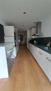 a kitchen with white cabinets and a wooden floor at Tróia Oasis Villa in Troia