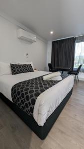 a bedroom with a large bed and a chair at Cooma High Country Motel in Cooma