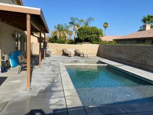 a swimming pool in a backyard with a brick wall at Walking Distance to Stagecoach in Indio