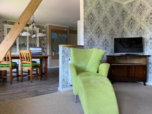 a living room with a green chair and a table at Ferienwohnung Am Museum in Dötlingen