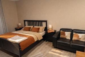 a bedroom with a bed and a leather couch at Apartment Riviera 13 Lipno in Lipno nad Vltavou