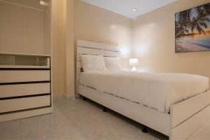 a bedroom with a large white bed and a dresser at Blue Lodge in Manati