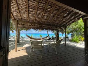 a porch with chairs and a hammock on the beach at Rangiroa Sunny House in Avatoru