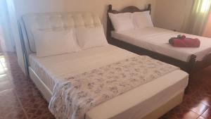 two beds in a hotel room with white sheets at Pacific View Apartment in Roseau