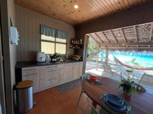 a kitchen with a table and a kitchen with a view at Rangiroa Sunny House in Avatoru