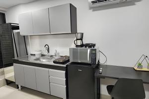 a kitchen with a sink and a microwave on a counter at Studio IX - Com Ar Condicionado - Jundiaí in Jundiaí