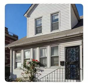 a white house with a door and flowers on it at New York Flushing private room in Flushing