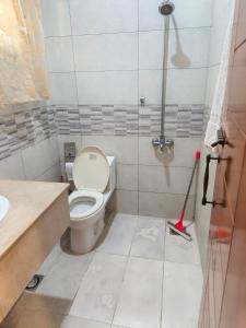 a bathroom with a toilet and a sink and a mop at The Aristocrat Manor in Islamabad +7 photos