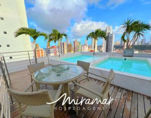 a balcony with a table and chairs and a swimming pool at Lindo flat no Manaíra Apart Hotel in João Pessoa