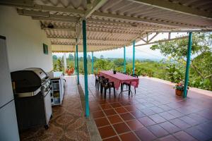 a patio with a table and chairs and a kitchen at Finca La Molienda, espléndido Mirador del Quindio in Circasia