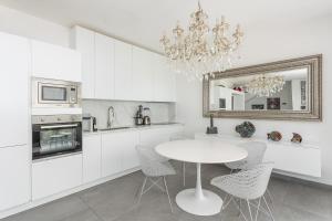 a white kitchen with a table and chairs and a mirror at Luxury beach front in Torre Grande