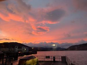 a boat docked at a dock with a sunset at Waterside House B&B in Ullapool