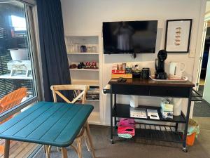 a living room with a table and a tv and a desk at Brophys Beach Studio in Whitianga