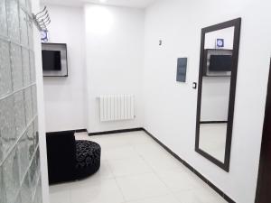 Habitación blanca con espejo y silla en Moderne Appart Tlemcen, en Tlemcen