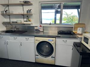 a kitchen with a washing machine under a counter at Brophys Beach Studio in Whitianga