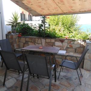 a table and chairs on a patio with a stone wall at Raptis House in Karavostamo