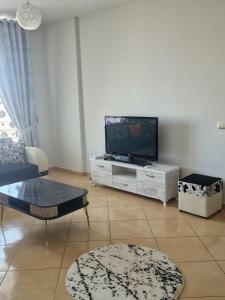 a living room with a flat screen tv on a cabinet at Elegant Apartment City Center in Fier