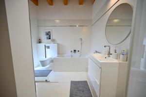 a white bathroom with a tub and a sink and a mirror at Villa OLIVA in Kľačany +16 photos