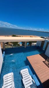 a swimming pool with two white chairs and the ocean at Paraná Beach Apart Hotel in Encarnación