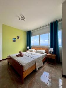 a bedroom with a large bed with blue curtains at Casa BB&Djassi - SUITES in Ponta do Sol +27 photos