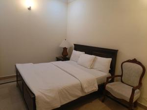 a bedroom with a white bed and a chair at The Aristocrat Residency in Islamabad