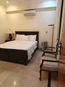 a bedroom with a bed and a chair in it at The Aristocrat Residency in Islamabad