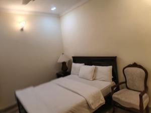 a small bedroom with a bed and a chair at The Aristocrat Residency in Islamabad +11 photos
