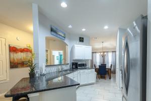 a kitchen with white cabinets and a stainless steel refrigerator at Modern Updates - Great Location - King Bed- BMT in San Antonio