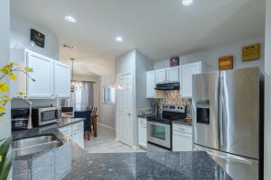 a kitchen with white cabinets and a stainless steel refrigerator at Modern Updates - Great Location - King Bed- BMT in San Antonio