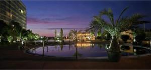 a large pool of water with palm trees at night at Sunset Beach Studio by Blaxy Resort Olimp in Olimp