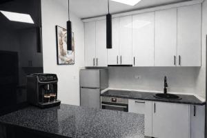a kitchen with white cabinets and a black counter top at Avis 1 in Igalo