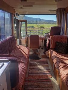 a living room with couches and a table and windows at Cruzo The House Bus in Takaka
