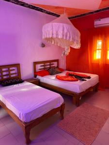 a bedroom with two beds and a chandelier at Hôtel évasion pêche djilor île sine saloum in Fatick
