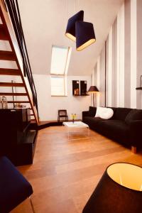 a living room with a black couch and a staircase at DEUXHOMMES Boutique B&B Massage&Spa in Hasselt