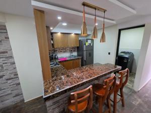 a kitchen with a counter with chairs and a refrigerator at Torres buambiles 2 in Ipiales