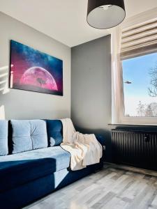 a living room with a blue couch and a window at Chopina Place in Oświęcim