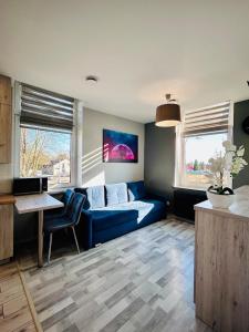 a living room with a blue couch and two windows at Chopina Place in Oświęcim